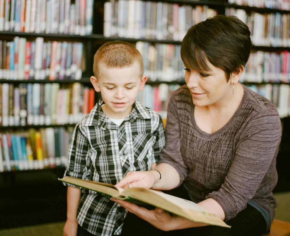 Frau liest Junge etwas aus einem Buch vor 