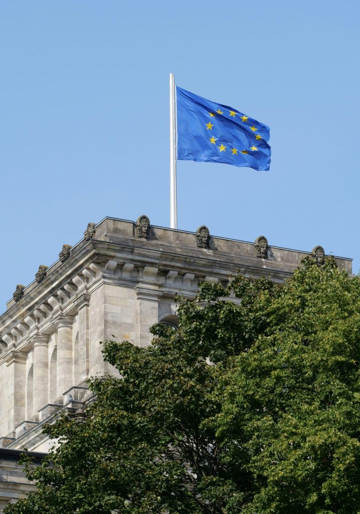European union flag flies over a stone building.